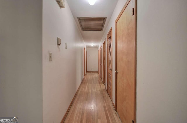 corridor featuring light wood-type flooring, visible vents, and baseboards