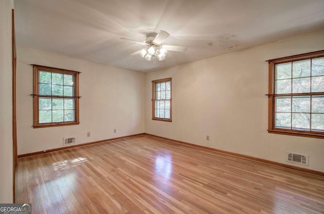 empty room featuring light wood-type flooring, visible vents, and baseboards