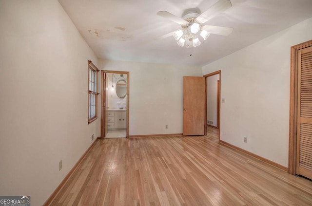 unfurnished bedroom featuring ensuite bathroom, a ceiling fan, baseboards, a closet, and light wood-type flooring