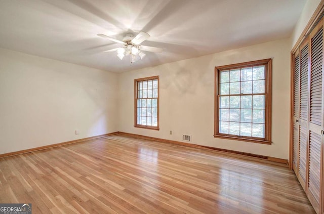 unfurnished bedroom featuring light wood finished floors, baseboards, visible vents, and a closet