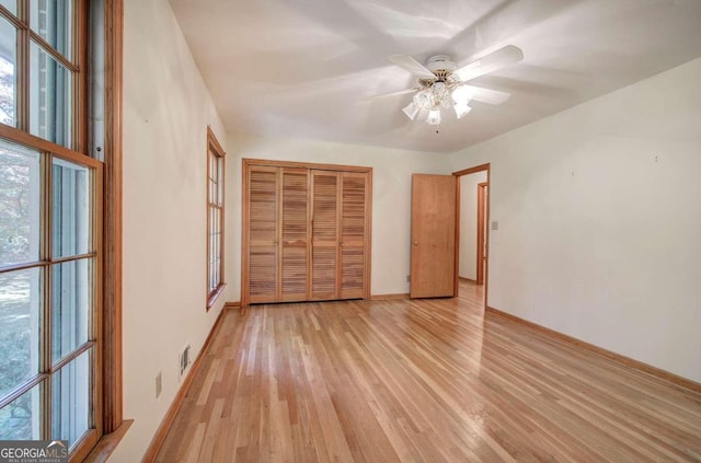 unfurnished bedroom featuring a closet, visible vents, light wood-style floors, a ceiling fan, and baseboards