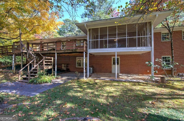 back of house with central air condition unit, a sunroom, a lawn, stairway, and a wooden deck