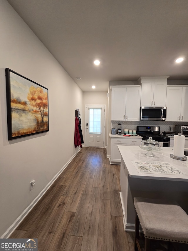 kitchen featuring white cabinetry, decorative backsplash, dark hardwood / wood-style floors, and stainless steel appliances