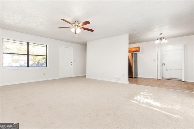 carpeted spare room with a textured ceiling and ceiling fan with notable chandelier