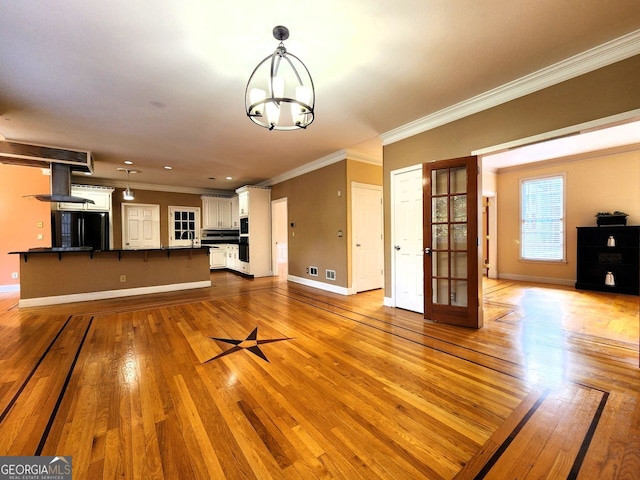 unfurnished living room featuring light wood-type flooring, a chandelier, and ornamental molding