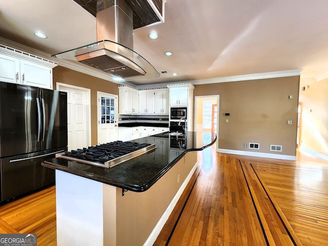 kitchen featuring island range hood, light wood-type flooring, white cabinets, and stainless steel appliances