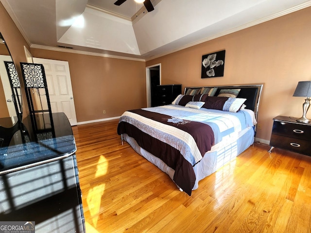 bedroom with ceiling fan, a raised ceiling, light hardwood / wood-style flooring, and crown molding