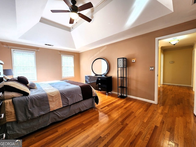 bedroom featuring crown molding, hardwood / wood-style floors, ceiling fan, and a raised ceiling