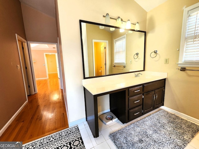 bathroom featuring vanity, wood-type flooring, lofted ceiling, and plenty of natural light