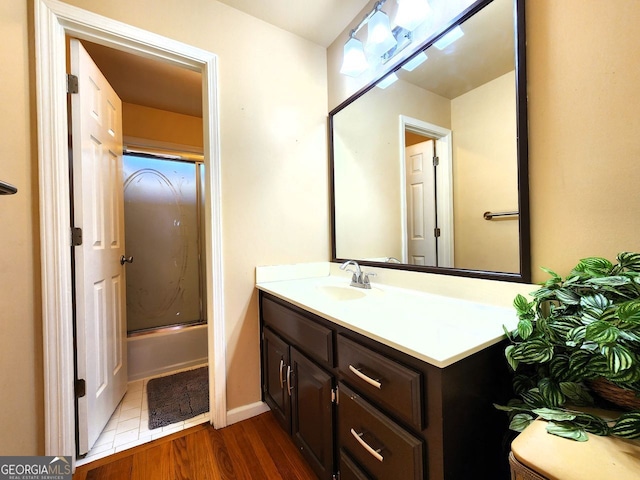 bathroom with shower / bath combination with glass door, wood-type flooring, and vanity