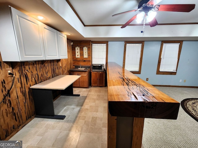 kitchen featuring wooden counters, white cabinetry, sink, ceiling fan, and a center island