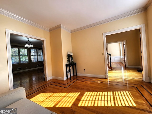 unfurnished living room with wood-type flooring, a chandelier, and crown molding