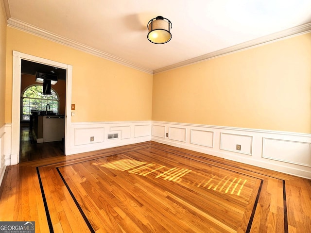 empty room featuring ornamental molding and hardwood / wood-style floors