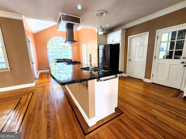 kitchen featuring white cabinetry, sink, extractor fan, decorative light fixtures, and black refrigerator