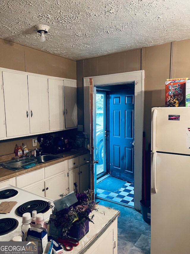 kitchen with sink, white cabinetry, white fridge, and a textured ceiling