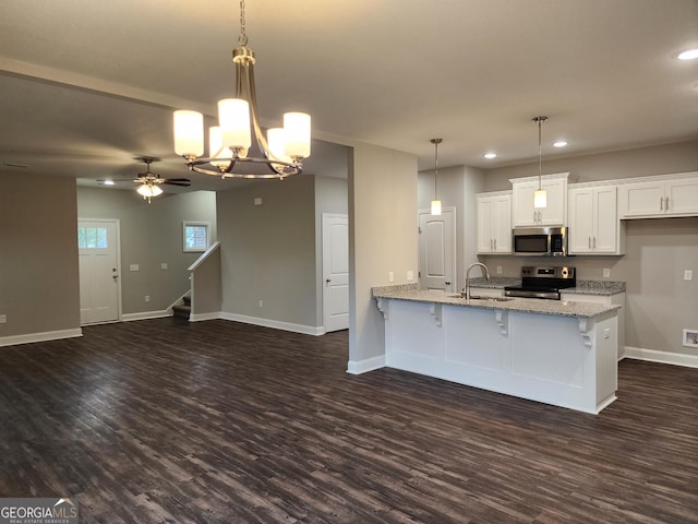 kitchen featuring dark hardwood / wood-style floors, stainless steel appliances, light stone countertops, pendant lighting, and white cabinets