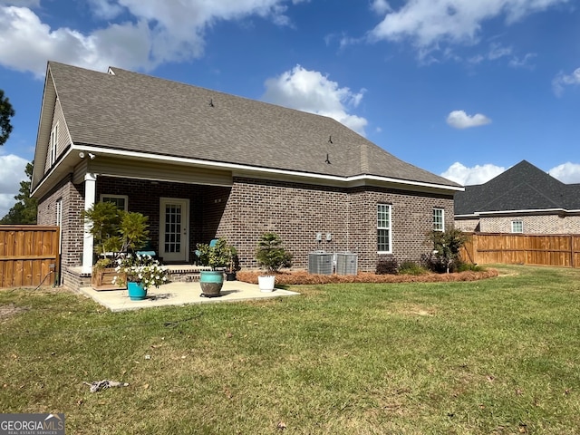 rear view of house with a patio, a lawn, and central AC unit