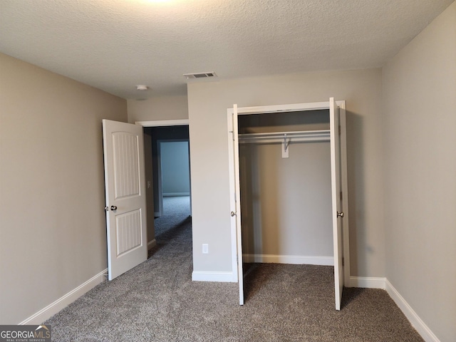 unfurnished bedroom featuring a closet, a textured ceiling, and dark carpet