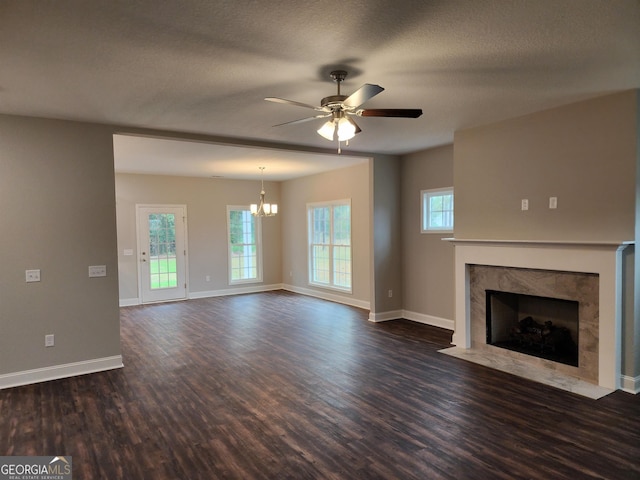 unfurnished living room featuring ceiling fan, a healthy amount of sunlight, and dark hardwood / wood-style floors