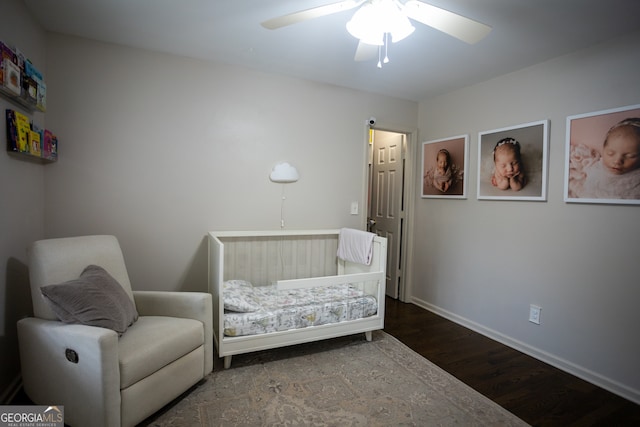 bedroom featuring ceiling fan, hardwood / wood-style floors, and a nursery area