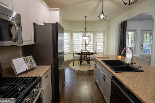 kitchen with dark hardwood / wood-style flooring, stainless steel appliances, sink, pendant lighting, and white cabinetry