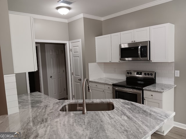 kitchen with light stone counters, appliances with stainless steel finishes, and white cabinets