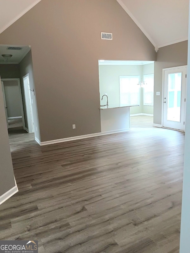 unfurnished room with a chandelier, ornamental molding, dark wood-type flooring, and high vaulted ceiling