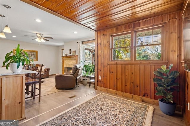 foyer entrance with ceiling fan, wood ceiling, light wood-type flooring, and wood walls