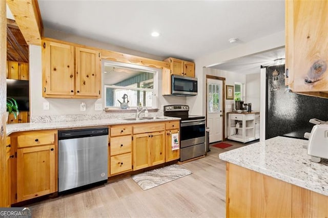 kitchen with light brown cabinets, light hardwood / wood-style flooring, stainless steel appliances, sink, and light stone counters