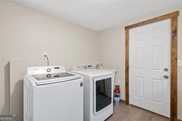 laundry area with washing machine and dryer and light hardwood / wood-style flooring