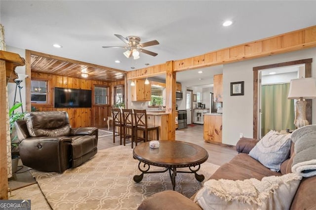 living room with ceiling fan and wood walls