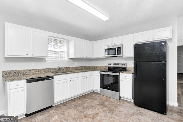 kitchen with white cabinets, light stone countertops, stainless steel appliances, and sink