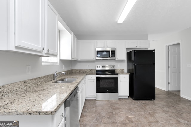 kitchen featuring white cabinetry, light stone counters, appliances with stainless steel finishes, and sink