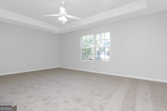 unfurnished room featuring ceiling fan, a raised ceiling, and carpet floors