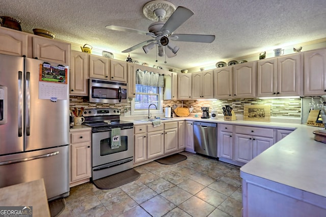 kitchen with appliances with stainless steel finishes, a textured ceiling, ceiling fan, and sink