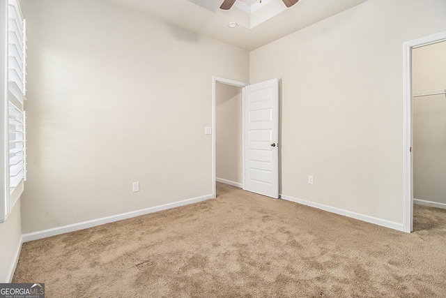 unfurnished bedroom featuring a walk in closet, ceiling fan, a closet, and carpet floors