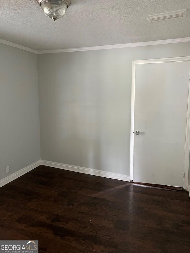 unfurnished room with dark hardwood / wood-style flooring, a textured ceiling, and ornamental molding