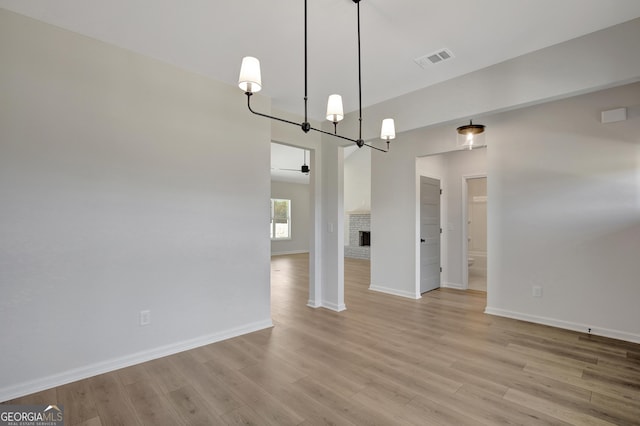 interior space with an inviting chandelier, a fireplace, and light hardwood / wood-style flooring