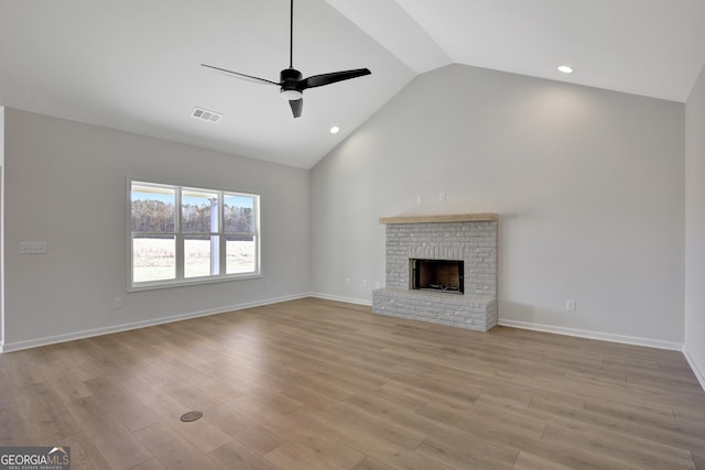 unfurnished living room featuring a brick fireplace, vaulted ceiling, light hardwood / wood-style flooring, and ceiling fan