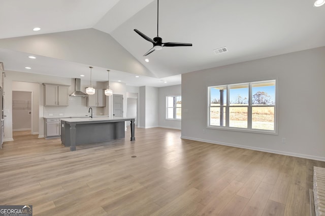 unfurnished living room featuring ceiling fan, light hardwood / wood-style flooring, high vaulted ceiling, and sink