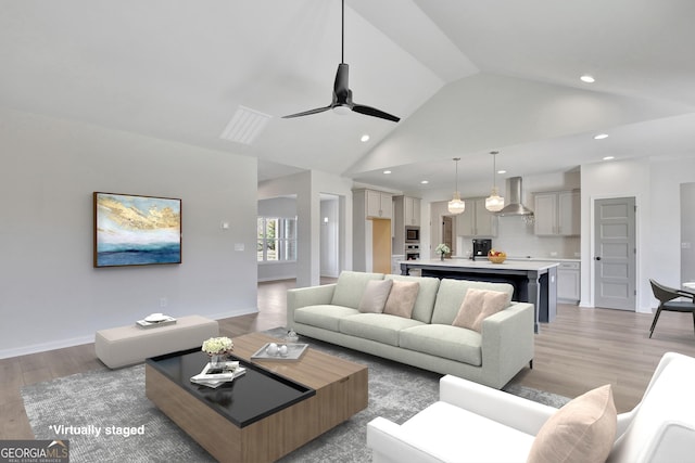 living room with ceiling fan, high vaulted ceiling, and light wood-type flooring