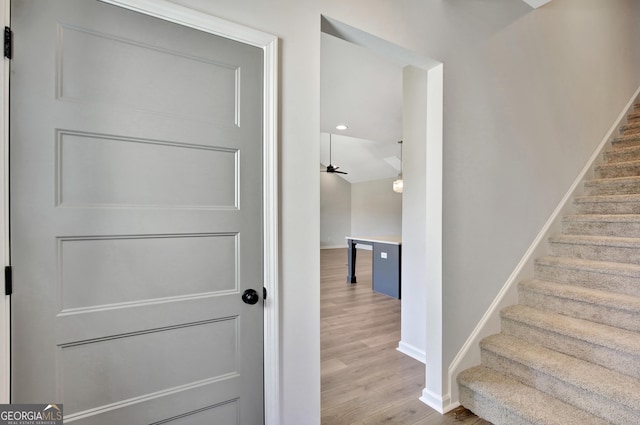 stairs featuring hardwood / wood-style floors and ceiling fan