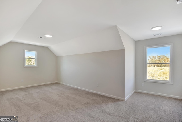 bonus room with lofted ceiling and light carpet