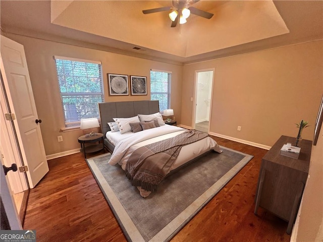 bedroom featuring ceiling fan, dark hardwood / wood-style floors, and a tray ceiling