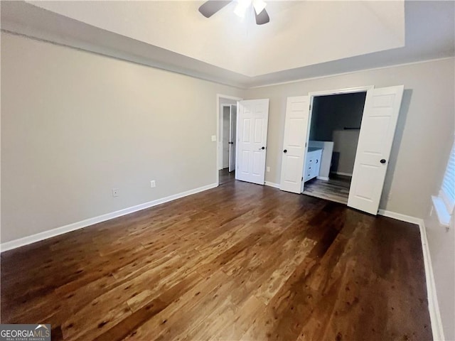 unfurnished bedroom featuring ensuite bathroom, dark hardwood / wood-style flooring, and ceiling fan