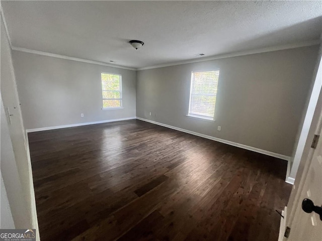 empty room featuring dark wood-type flooring, a textured ceiling, and ornamental molding