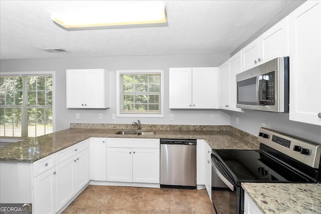 kitchen featuring sink, white cabinetry, stainless steel appliances, and plenty of natural light