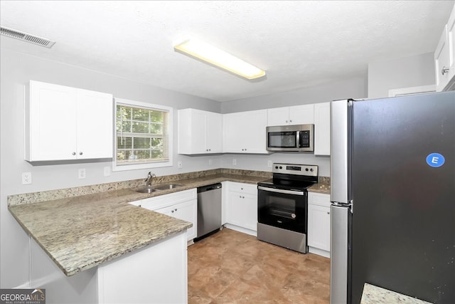 kitchen with appliances with stainless steel finishes, sink, kitchen peninsula, and white cabinets