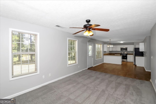 unfurnished living room with a textured ceiling, light colored carpet, and plenty of natural light