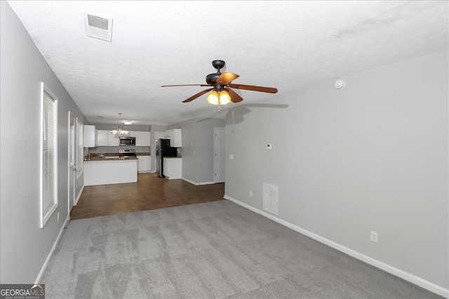 unfurnished living room featuring light carpet, a textured ceiling, and ceiling fan with notable chandelier